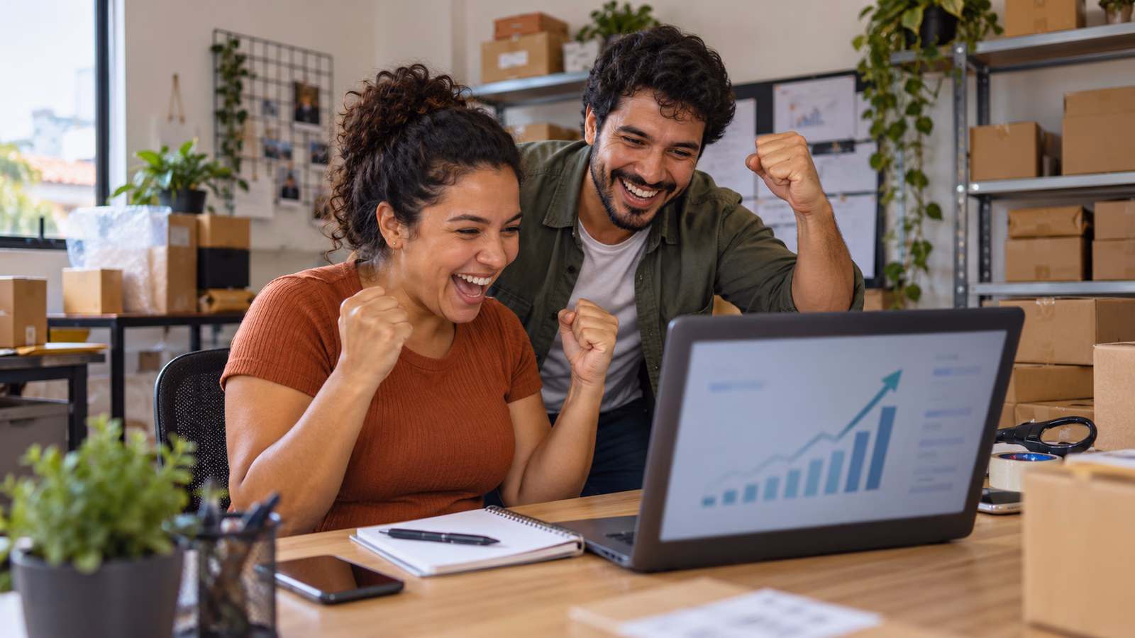 Dupla de uma loja online comemora o aumento de pedidos em frente ao notebook