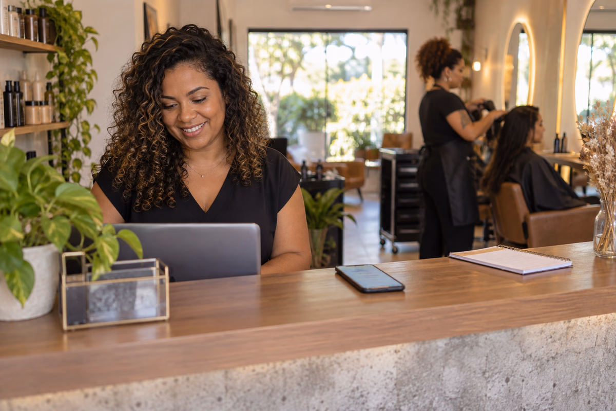 Dona de um salão de beleza trabalhando tranquila no balcão, com o celular ao lado atendendo os clientes